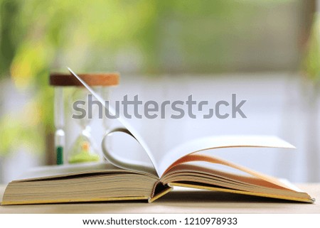 Close-up shots of books opened in the garden. Hourglass is the background selective focus and shallow depth of field
