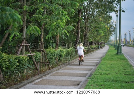 woman is riding bicycle on walk way and bike lane at Bangkok Thailand 