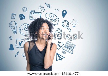 Smiling african american woman talking on phone standing near gray wall with blue computer and internet drawing on it. Toned image