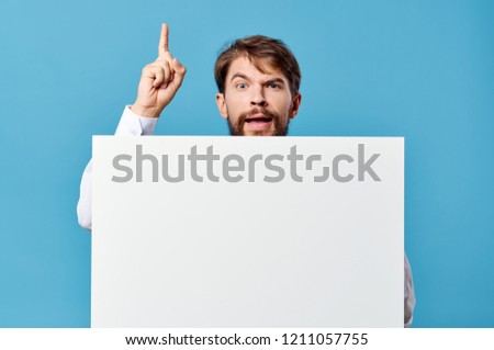  mockup, poster  man shows his index finger up and a white sheet of paper on a blue background                            