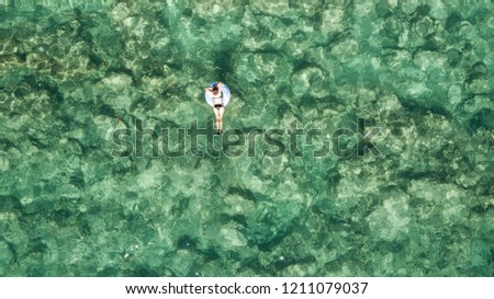 Aerial view of young brunette woman swimming on the inflatable big circle in turquoise sea. Top view of slim lady relaxing on her holidays in Thailand, Phuket.