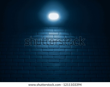 One bright  lamp top of the brick wall blue toned background