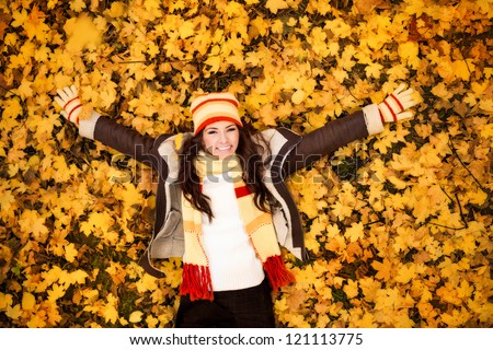 autumn woman lying over leaves and smiling, top view