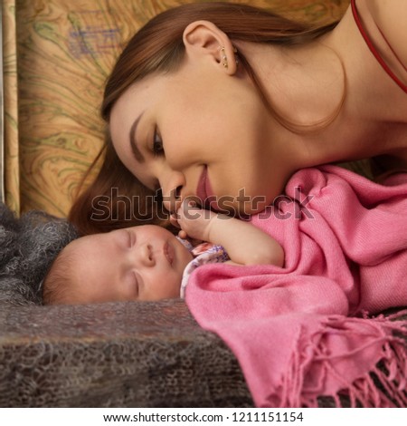 Close-up pretty woman kisses a newborn baby in her arms