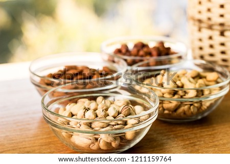 Assortment of mixed nuts and wicker basket on wood table background 