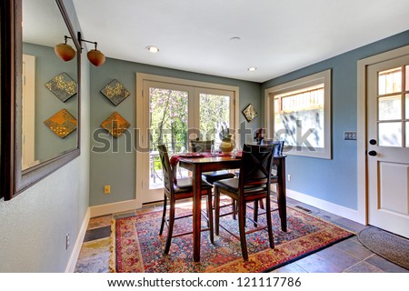 Blue bright dining room with red rug and high table.