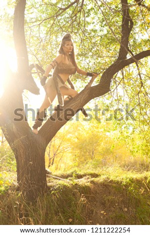 Girl in the Amazon suit posing on nature on a sunny evening. Cosplay. Toned photo.