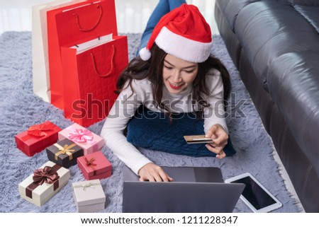 woman in santa hat shopping online for Christmas gift with laptop in the living room
