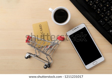 The concept of online shopping. Composition with discount cards and a shopping trolley and a telephone on the background of the table