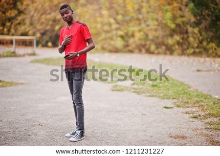 African american man in red football sport t-shirt against autumn park.