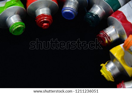 Acrylic color tubes on black background and space for text