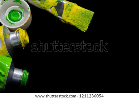Acrylic color tubes and brush on black background and space for text