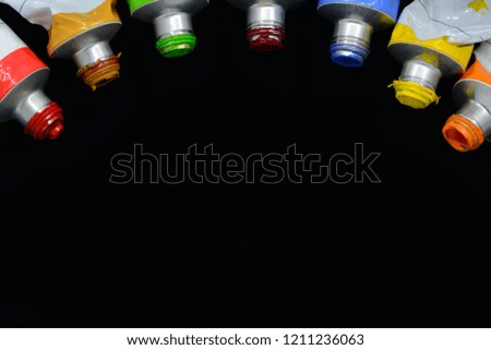 Acrylic color tubes on black background and space for text