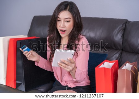 surprised woman using laptop computer for online shopping with credit card in the living room