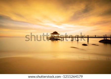 A small jetty, pier speed boat on the beach sunset orange color sky at Koh Kood island of Thailand.