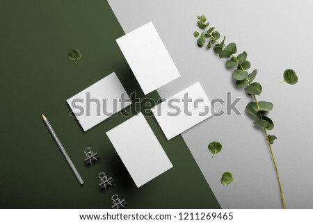 Business cards blank mockup and stationery set, with floral elements, top view, on white and green background.