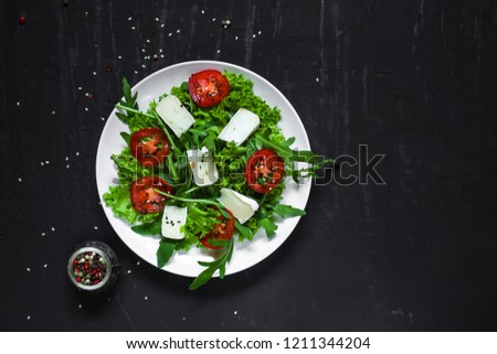 salad - arugula, cheese, tomatoes, lettuce and sesame (Healthy salad from fresh vegetables). Vegan food. Flat lay. Diet menu. Top view

