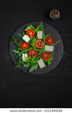 salad - arugula, cheese, tomatoes, lettuce and sesame (Healthy salad from fresh vegetables). Vegan food. Flat lay. Diet menu. Top view

