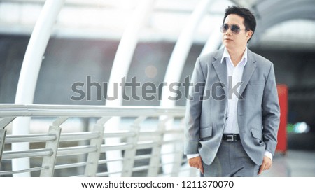 Handsome asia businessmanwalking to office on skywalk at metro station in center business area