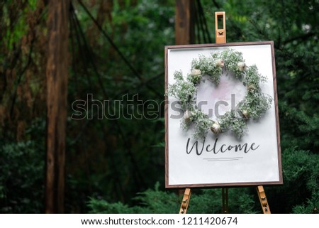 The easel is wooden with a frame plate and the words welcome. Index of events in the forest, wedding decor.