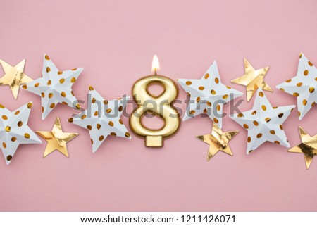 Number 8 gold candle and stars on a pastel pink background