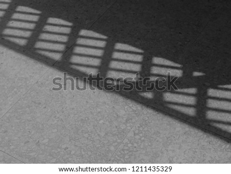 monochrome picture of diagonal shadows of fence across veranda.