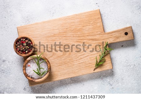 Wooden cutting board with sea salt and pepper on white stone table. Top view copy space. Royalty-Free Stock Photo #1211437309
