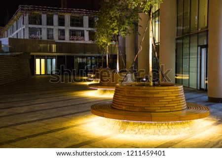 round wooden bench in the backlit street
