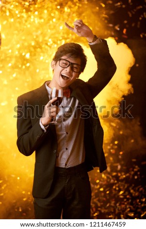 Handsome young man in glasses dancing in nightclub with wine glass in hand