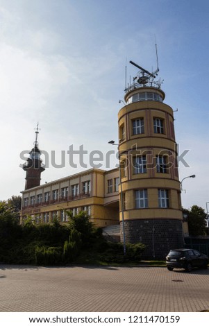 Administration of the port in the city of Gdansk. The inscription on the facade is translated as "Captain of the Port". In the background there is a historic building of the lighthouse. Poland