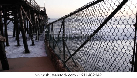 Background plate of Silhouetted chain-link fence next to the pier and the ocean