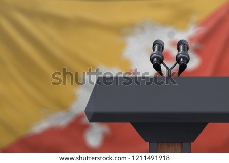 Podium lectern with two microphones and Bhutan flag in backgroun