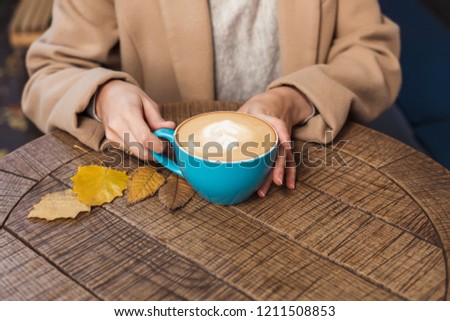 Girl's hands holding a hot cup of coffee close-up. Autumn Royalty-Free Stock Photo #1211508853
