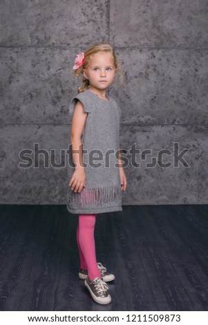 Kid model, girl in a gray dress, flower decoration in a hair