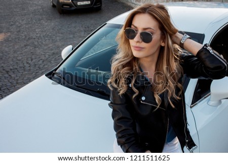 Beautiful and stylish young blonde woman. Portrait on the background of her car