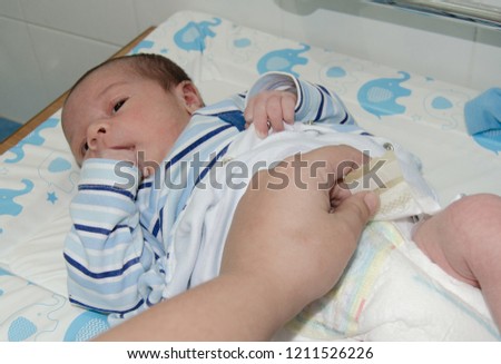 mother hand changing newborn baby on baby changer, relaxed baby