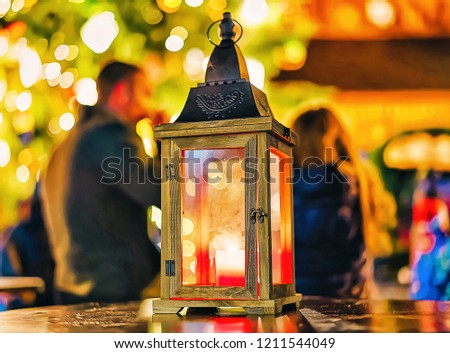 Lantern with the candle inside of it pictured in the middle of the Christmas market in winter Riga in Latvia.