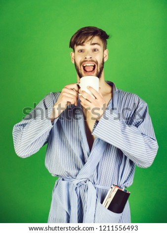 relax of smiling man in bathrobe holding cup of coffee and newspaper on blue background