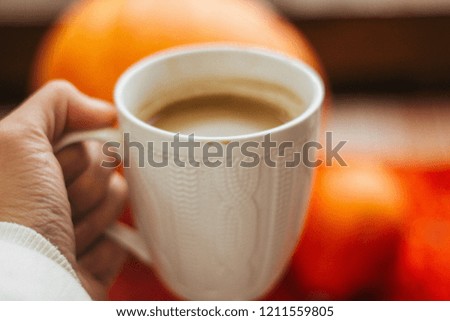 White cup of hot coffee on orange background.