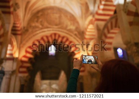 Young female tourist taking a picture with her phone to the mosque