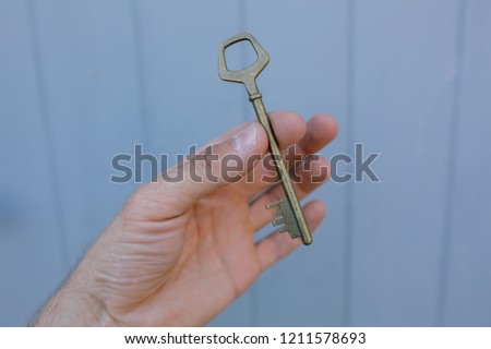 Old vintage brass door Key in mans hand