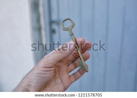 Old vintage brass door Key in mans hand