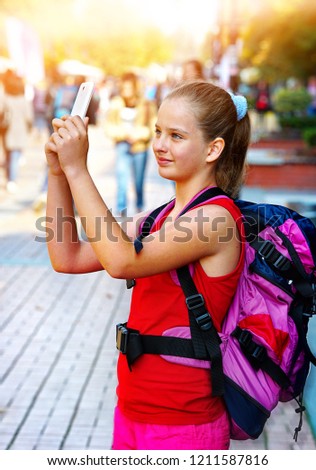 Tourist girl with backpack taking selfies on smartphone and cultural city showplace pedestrianized street outdoor.