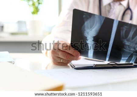 Male doctor hold in arm silver pen and look at xray photography closeup. Skeleton bone disease exam medic aid or cancer physical test in hospital for healthy lifestyle education career concept