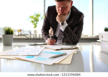 Silver pen lie at important paper on table in office closeup with businessman in background. Paperwork job trade balance bank credit loan money invest payment irs commerce partnership concept