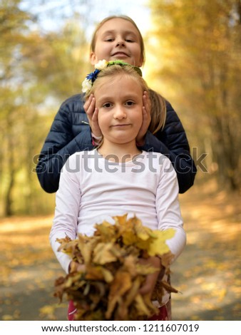 Two sisters having fun in the autumn park 
