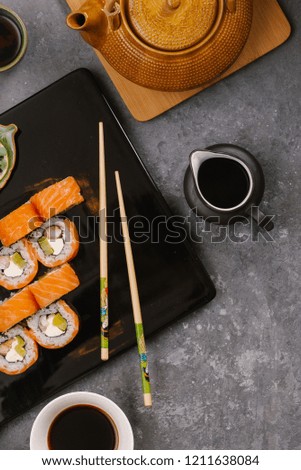 Japanese sushi on a rustic dark background. Sushi rolls, nigiri, maki, pickled ginger, wasabi, soy sauce. Sushi set on a table. Space for text. Top view. Sushi background. Asian or Japanese food frame