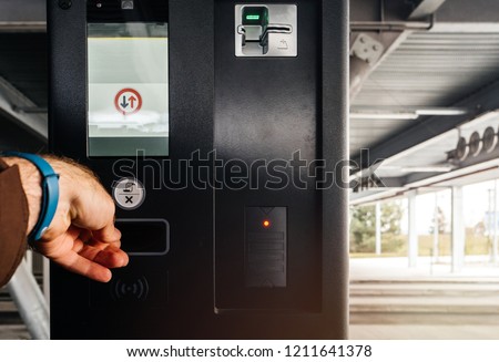 Male hand taking ticket from the parking barrier teller at the exit of modern parking 