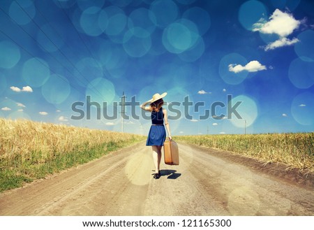 Lonely girl with suitcase at country road.  Photo with bokeh at background. Royalty-Free Stock Photo #121165300