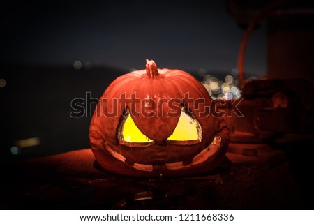 Horror Halloween concept. Close up view of scary dead Halloween pumpkin glowing at dark background. Rotten pumpkin head. Selective focus